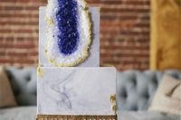 a grey marble wedding cake decorated with gold leaf and a large sugar geode in purple for an elegant wedding