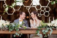 a honeycomb wedding backdrop with greenery and white blooms is a lovely idea for a rustic wedding