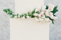 a laconic white square wedding cake decorated with a branch of white blooms is a stylish idea for a minimalist wedding