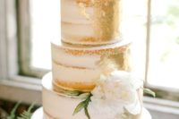 a large naked wedding cake with gold leaf and a single white flower is a super chic and elegant idea
