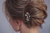 a messy twisted chignon with locks down and a small rhinestone hairpiece on one side