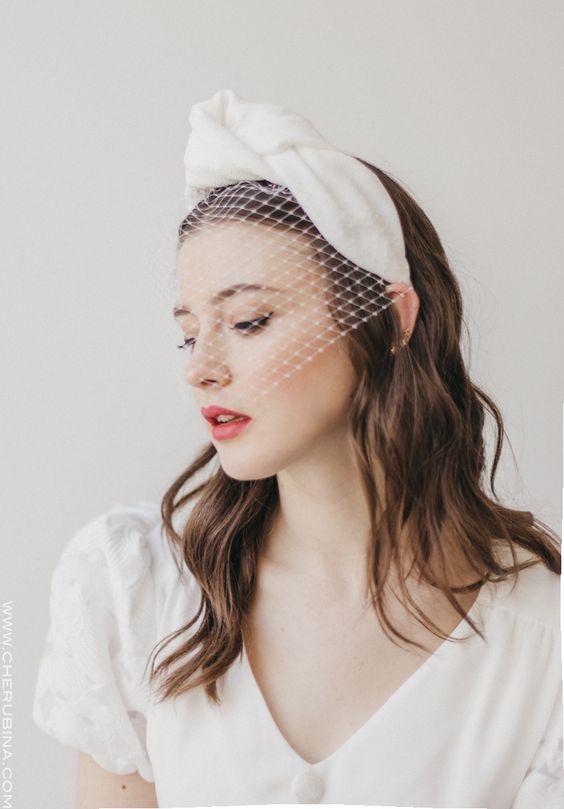a mini birdcage veil with a large silk bow on top is a modern and bold idea for a fashion-forward bride