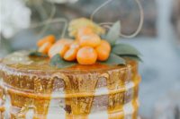 a naked wedding cake topped with hone, with kumquats and greenery is a gorgeous idea for a summer or fall wedding