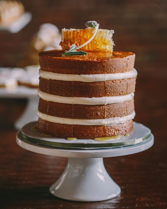 a naked wedding cake topped with honeycombs and herbs is a simple and cool idea for a relaxed or rustic wedding