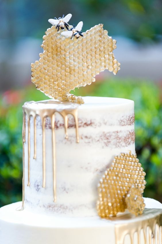 a naked wedding cake with gold drip and honeycombs and beeds of sugar is a lovely idea for a honey-themed wedding