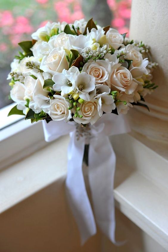 a neutral wedding bouquet of white freesia, blush roses, berries and foliage is a cool idea for an elegant wedding