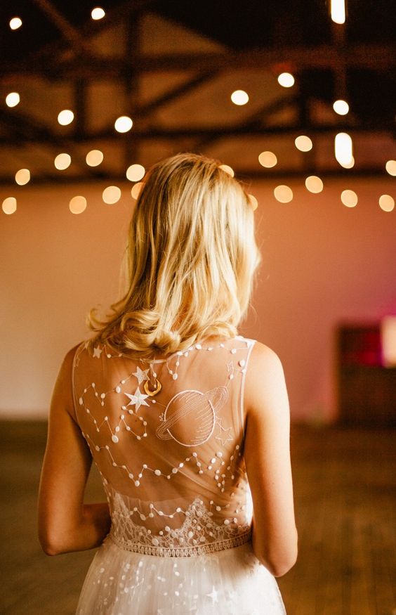 a neutral wedding dress with a super whimsical back done with stars, constellations and planets is great for an astronomy bride