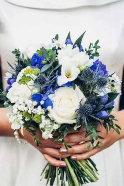 a pretty and bold wedding bouquet of white blooms, blue irises, thistles and some greenery and baby's breath is amazing
