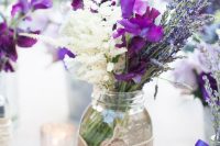 a pretty rustic wedding centerpiece of white lisianthus, purple freesia, lavender and a jar with burlap for a summer wedding