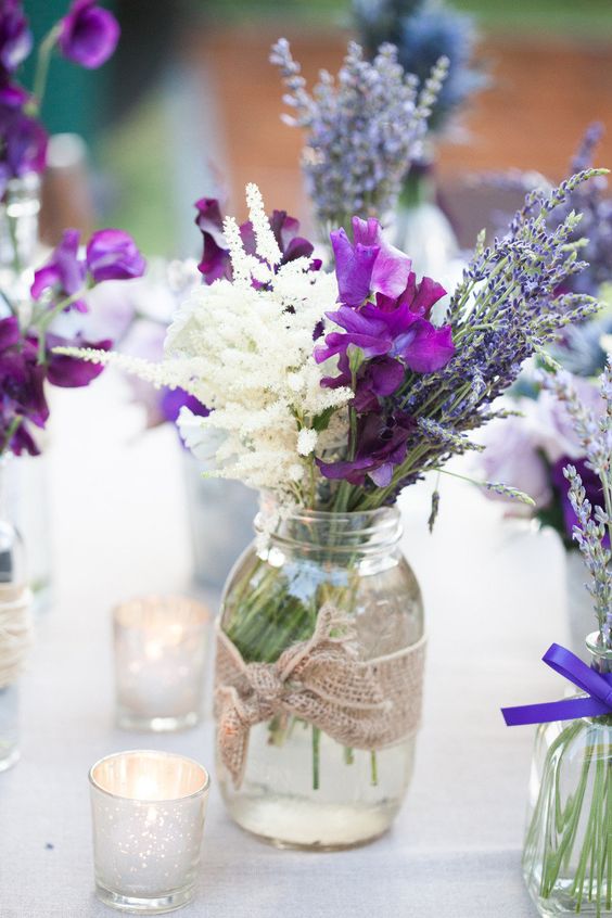a pretty rustic wedding centerpiece of white lisianthus, purple freesia, lavender and a jar with burlap for a summer wedding