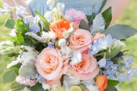 a pretty wedding bouquet of pink roses, coral ranunculus, blue delphinium, greenery and pale foliage is a chic idea