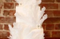a pure white square wedding cake with embellishments and white feathers is very lovely