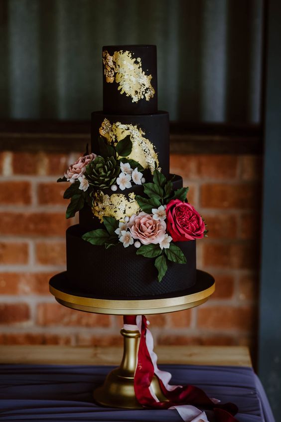 a refined black wedding cake with gold leaf, greenery and bold blooms is a stylish and very chic idea to try