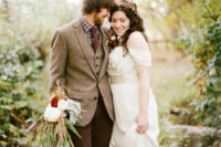 a relaxed groom’s outfit with brown pants, a tan tweed blazer and waistcoat, a checked button down, a burgundy tie