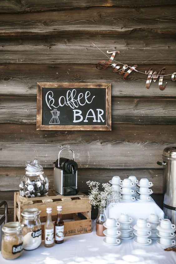 a rustic coffee bar with a chalkboard sign, crates, mugs, sweets and cream is a cute and cozy idea