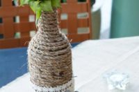 a rustic wedding centerpiece of a twine wrapped bottle with a sunflower and horseshoes