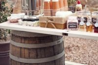 a simple rustic wedding coffee bar of two barrels and a tabletop plus lots of sweets, cups and syrups there