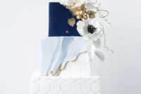 a sophisticated wedding cake with a white hex, watercolor blue and gold and navy tiers and sugar blooms and berries