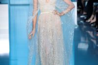 a sparkling neutral wedding dress with a plunging neckline and a cape over the dress