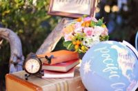 a stack of vintage suitcases, books, right blooms, a fun plane, a globe and a sign is cool decor for a vintage travel-themed wedding