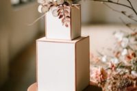 a stylish modern wedding cake with copper framing, copper herbs and foliage and white blooms