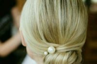 a super elegant twisted low bun with pearl pins and a sleek top for a minimalist bride