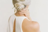 a twisted low bun with a volume on top and a statement hair pin for a minimalist bride