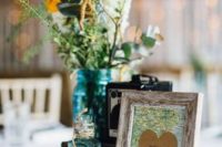 a vintage travel-themed wedding centerpiece of a vintage camera, neutral blooms and greeneyr, a map sign