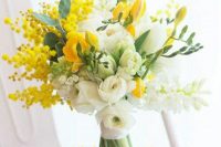 a virbant wedding bouquet of white and yellow tulips and freesia, yellow mimosa and greenery for a spring wedding