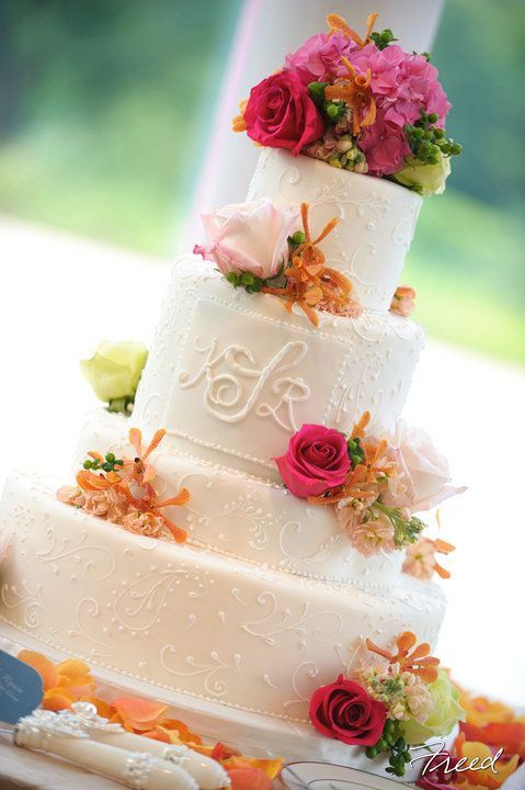 a white patterned wedding cake with monograms and colorful blooms and greenery is a cool idea for a summer wedding