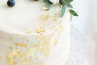 a white wedding cake with gold leaf, greenery and berries on top is a stunning idea for a casual wedding