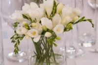 a white wedding centerpiece of a simple glass vase and freesia is a lovely idea for a modenr or minimalist wedding