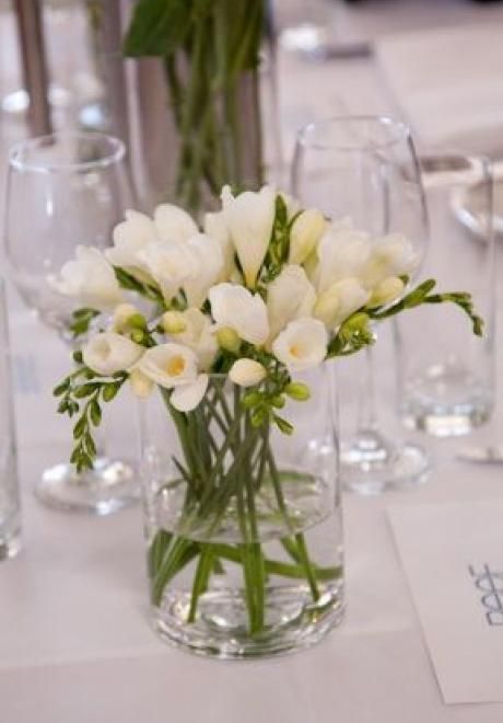 a white wedding centerpiece of a simple glass vase and freesia is a lovely idea for a modenr or minimalist wedding