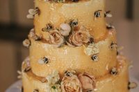 a yellow honeycomb wedding cake with pastel and neutral blooms and bees topped with honey is a lovely idea for summer