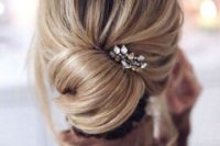 an elegant and effortlessly chic chignon with some locks down and a bump on top plus a rhinestone hairpiece