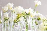an elegant cluster wedding centerpiece of mismatching vases and white freesia is a gorgeous idea for a modern wedding