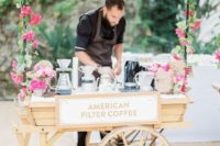 an elegant coffee bar decorated with pink blooms and greenery and styled as a vintage cart looks very chic