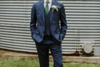 an elegant groom’s outfit with a thre-epiece navy suit, an emerald tie, a white button down and black shoes