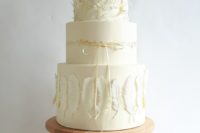 an ethereal white wedding cake with feather tiers and a plain one with gold leaf plus a ribbon bow