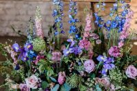 beautiful and lush wedding decor with pink roses, blue irises and lots of greenery is a gorgeous idea to rock