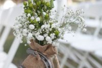 wedding aisle chair decor done with baby’s breath, berries, a burlap sack with a horseshoe