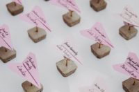 wedding escort cards with concrete and pink paper planes on top to match the travel-themed wedding