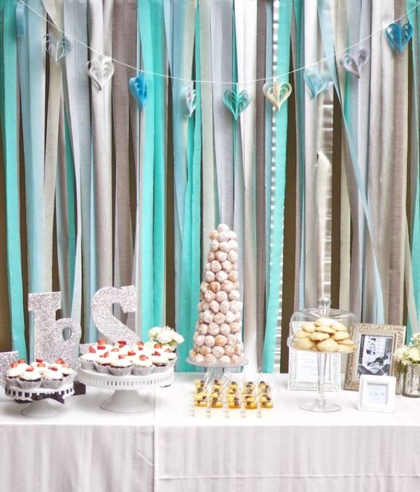 a dessert table with a silver, cream and tiffany blue ribbon backdrop to create an ambience
