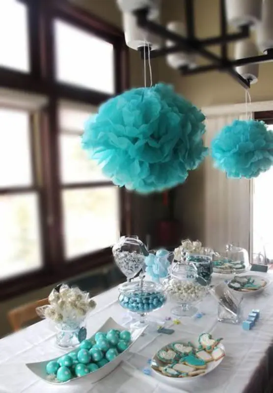 a dessert table with sweets in white and tiffany blue and with tiffany blue paper clouds over the table