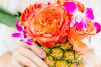 a tropical bridal shower centerpiece of a pineapple with bright florals
