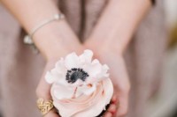 a cupcake with pink forsting and a white anemone on top is a lovely dessert idea for a spring or summer wedding