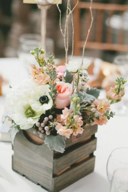 a neutral rustic wedding centerpiece of a crate with white anemones, pink peony roses and other blooms, berries and greenery plus some twigs