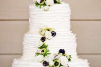 an eye-catchy white buttercream wedding cake decorated with white anemones and greenery plus black and white puzzle piece chocolate cake toppers is all cool