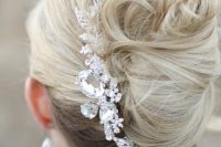 a super messy and chic French twist updo with messy waves and a large rhinestone hairpiece