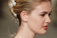 a French twisted updo with a textural top and large pearl pins that make it elegant and refined